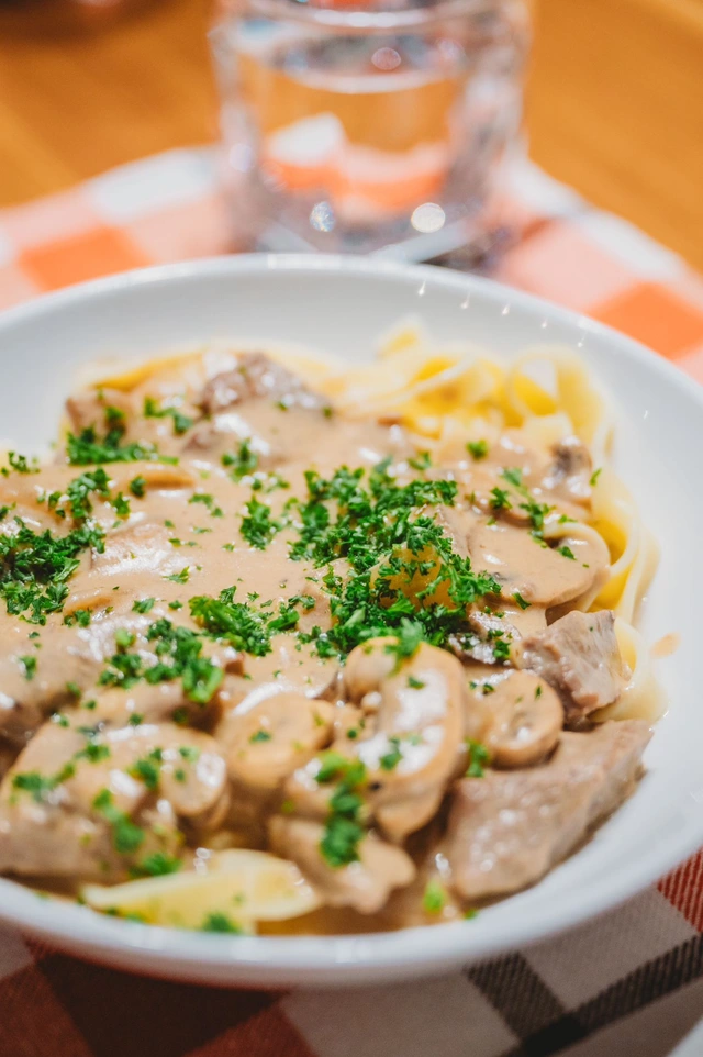Beef stroganoff with mushrooms over fettuccine, topped with fresh parsley