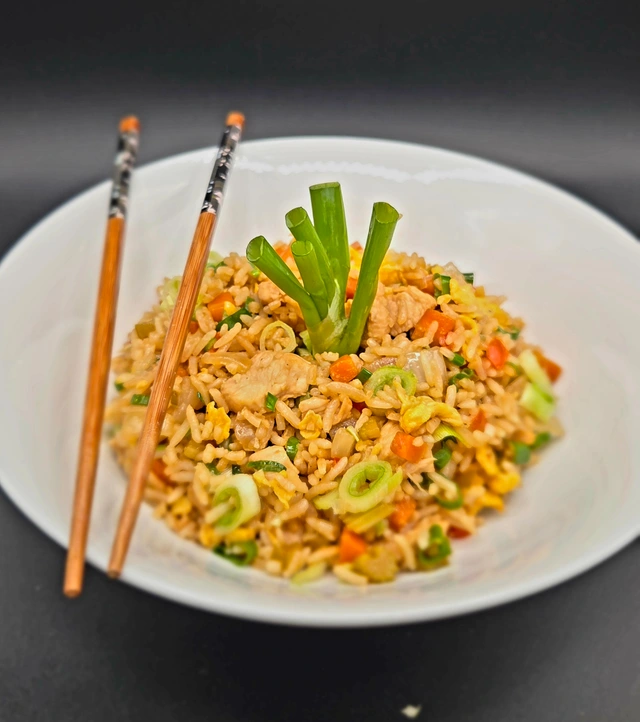 Chicken fried rice with vegetables and green onion, served with chopsticks
