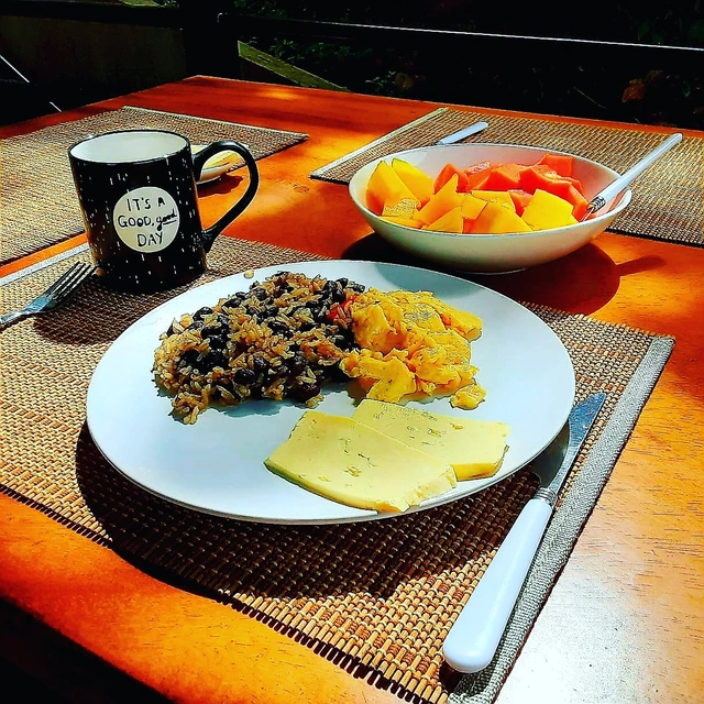 Costa Rican gallo pinto breakfast with scrambled eggs, cheese, fresh fruit, and coffee