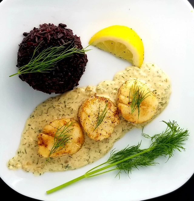 Seared scallops in a creamy dill sauce with black rice and fresh dill